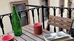 A wooden table with two red mugs and a green bottle, a wooden chair, and a magazine on the table. - Redecorated Flat With Huge Library 100mbps (Istanbul)