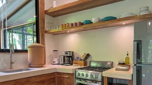 Uma cozinha compacta com fogão embutido, cafeteira e liquidificador na bancada.