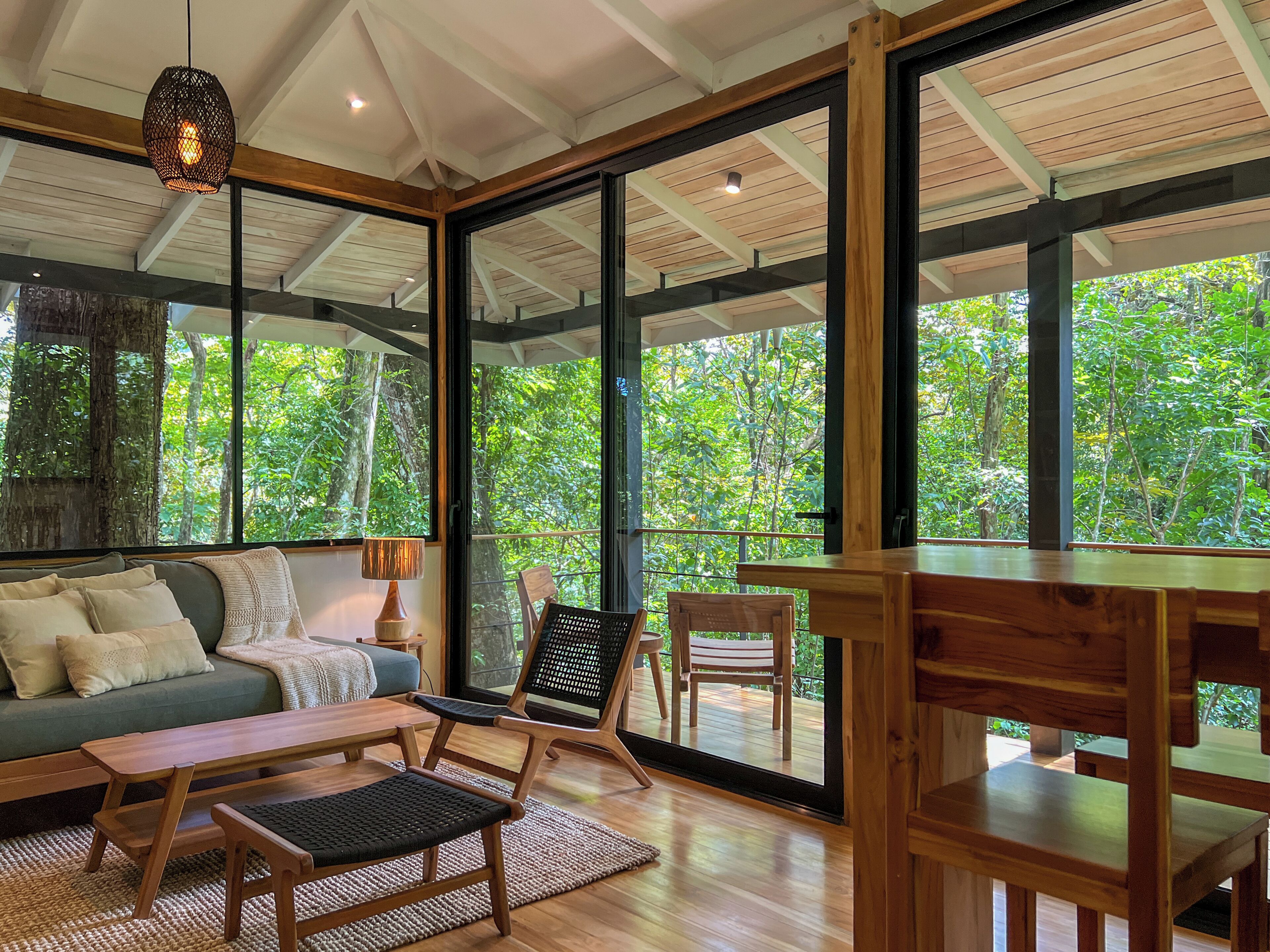 A spacious room with a large sliding glass door leading to an outdoor deck, a wooden bench, a sofa, and a table.