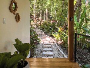 A wooden staircase leading to a garden with a stone pathway, surrounded by lush greenery and plants.