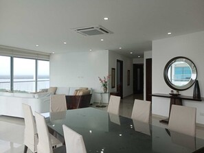 Ein moderner Essbereich mit einem Glastisch und Stühlen, einer Couch und Blick ins Freie.