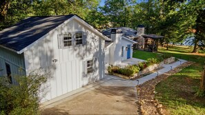 A white house with a blue door, a stone chimney, and a deck with string lights.