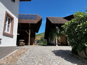 Un carrer empedrat que condueix a un edifici amb teulada inclinada i panells solars.