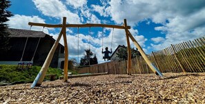 A wooden swing set in a backyard with a house and a fence in the background. - Suite with Breakfast, Free Wi-Fi & Parking, Near City Center (Gengenbach)