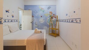 Un dormitorio con una cama, una escalera de madera y un muro decorado con motivos espaciales.
