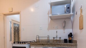 Una cocina con estufa a gas, horno, microondas y un refrigerador pequeño.