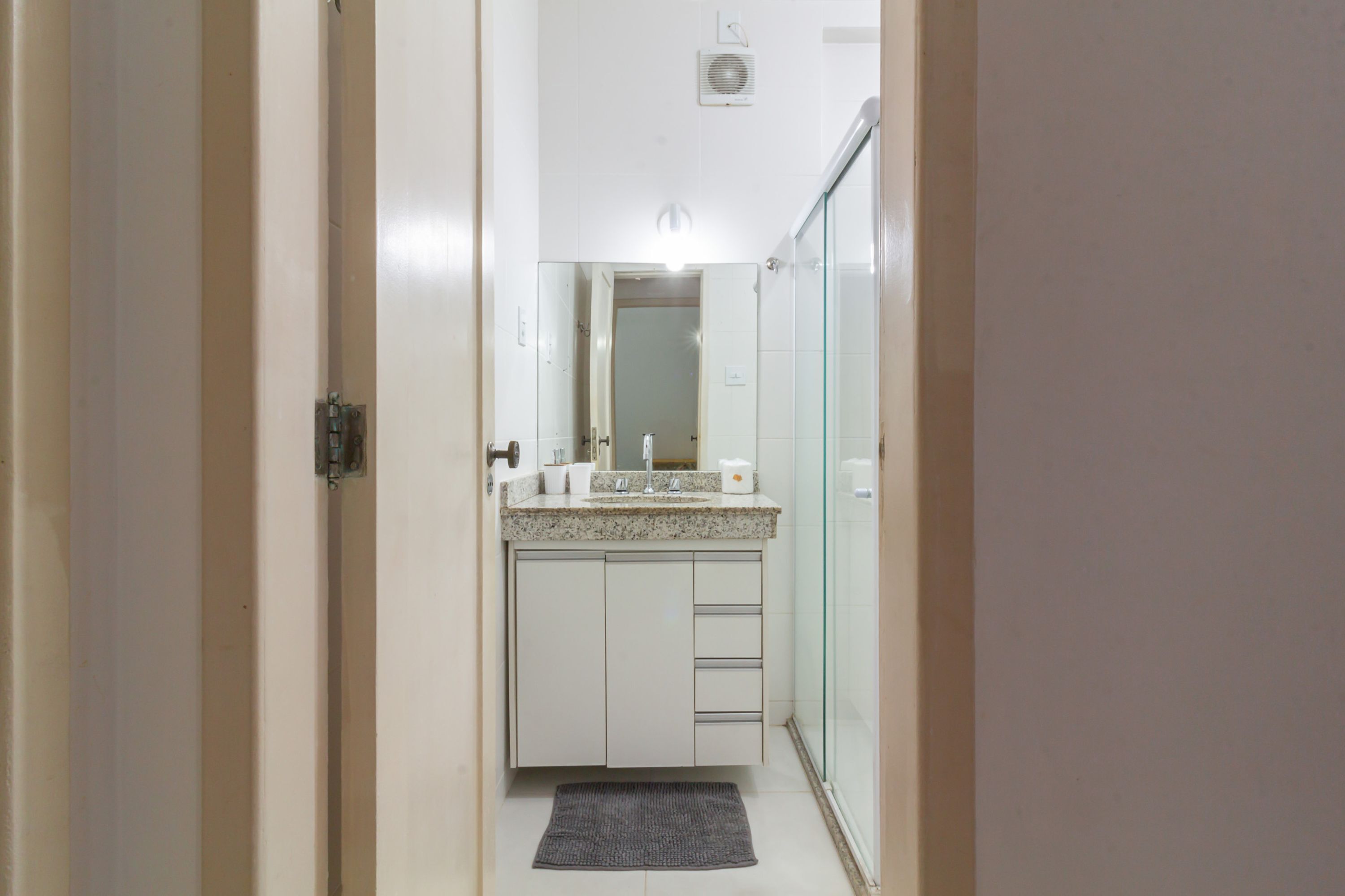Une salle de bain équipée d’un lavabo, d’un miroir et d’une douche à parois en verre.