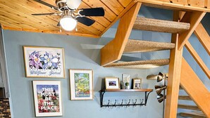 Ein Essbereich mit einem runden Tisch, grünen Stühlen, einem Deckenventilator und einer Treppe.