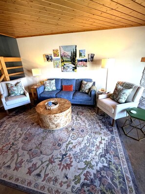 A living room with a blue sofa, two white armchairs, a round coffee table, and a patterned rug. - Elevated Oasis-3BR-Mt. CB-Garage-Hot Tub-Mountain Views (Crested Butte)