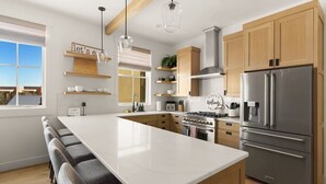 A modern kitchen with a large island, wooden cabinets, stainless steel appliances, and a view of the outdoors. - Rooftop Views, Walk to Downtown, Sleeps 13 (Buena Vista)