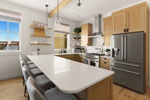 A modern kitchen with a large island, wooden cabinets, stainless steel appliances, and a view of the outdoors. - Rooftop Views, Walk to Downtown, Sleeps 13 (Buena Vista)