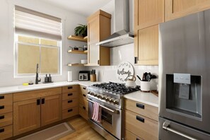 A modern kitchen with wooden cabinets, a stainless steel stove, and a built-in water dispenser. - Rooftop Views, Walk to Downtown, Sleeps 13 (Buena Vista)