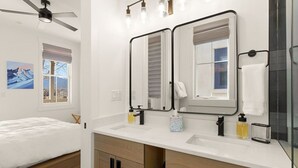 A modern bathroom with a double vanity, a ceiling fan, and a large mirror. - Rooftop Views, Walk to Downtown, Sleeps 13 (Buena Vista)