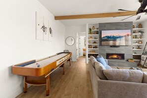 A living room with a pool table, a sofa, a fireplace, and a TV mounted on the wall. - Rooftop Views, Walk to Downtown, Sleeps 13 (Buena Vista)