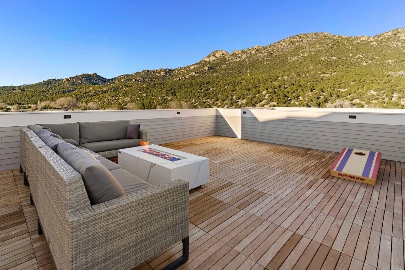 A rooftop terrace with a sofa, a coffee table, and a backyard game.