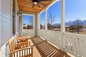 A covered porch with a table and chairs, wooden ceiling, and a view of mountains. - Rooftop Views, Walk to Downtown, Sleeps 13 (Buena Vista)