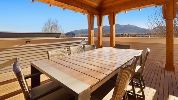 A wooden deck with a table and chairs, overlooking a mountainous landscape. - Rooftop Views, Walk to Downtown, Sleeps 13 (Buena Vista)