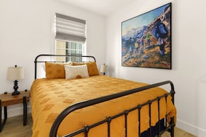A bedroom with a bed, a nightstand, a lamp, a window with blinds, and a painting on the wall. - Mountain Views | Apt Walk to Downtown | Sleeps 6 (Buena Vista)