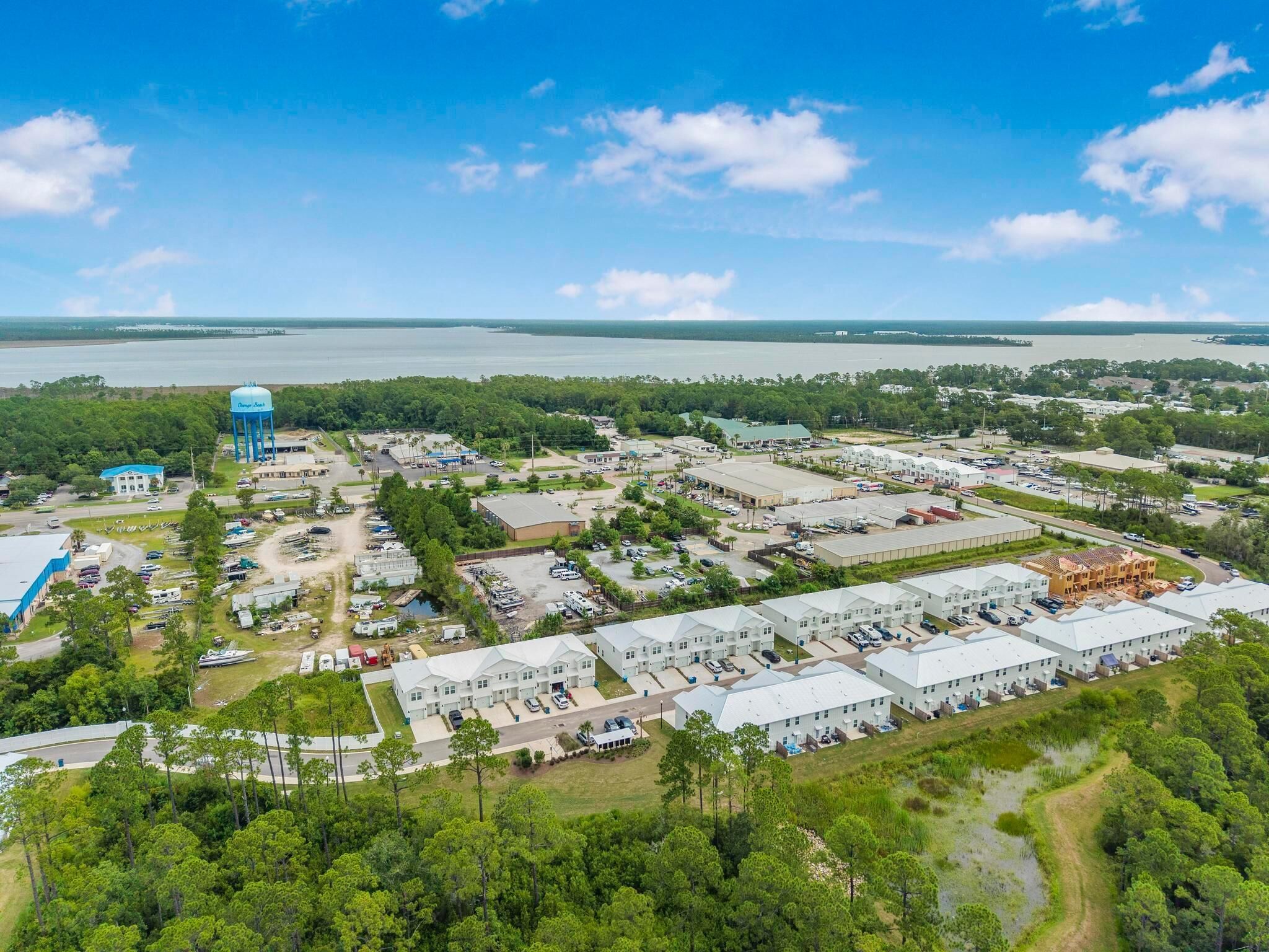 An aerial view of a coastal industrial area with warehouses, a water tower, and a marina.