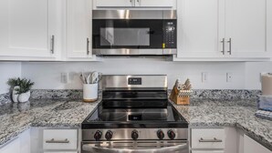 A kitchen with white cabinets, a stainless steel microwave, and a gas stove. - Lost Bay Townhome 4239 (Orange Beach)