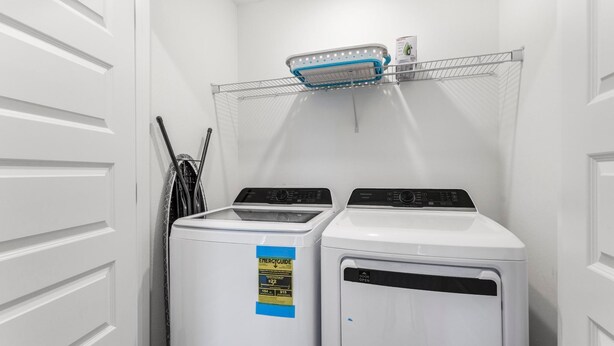 A laundry room with two front-loading washing machines and a drying rack above them. - Lost Bay Townhome 4239 (Orange Beach)