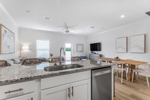 A modern kitchen with a granite countertop, stainless steel sink, and a built-in dishwasher. - Lost Bay Townhome 4239 (Orange Beach)