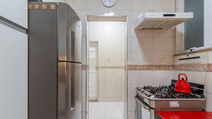 Eine Küche mit einem Edelstahl-Kühlschrank, einem Gasherd mit einem roten Wasserkocher und einer Uhr an der Wand.