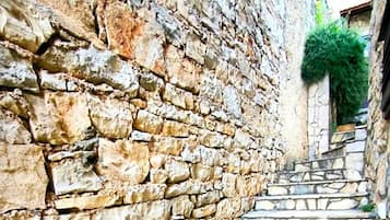 A stone staircase leading up to a building with a rough-textured wall.