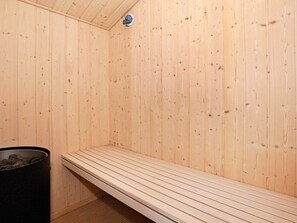 A sauna room with wooden walls, a bench, and a trash bin. - 4 Star Holiday Home in Hadsund (Hadsund)