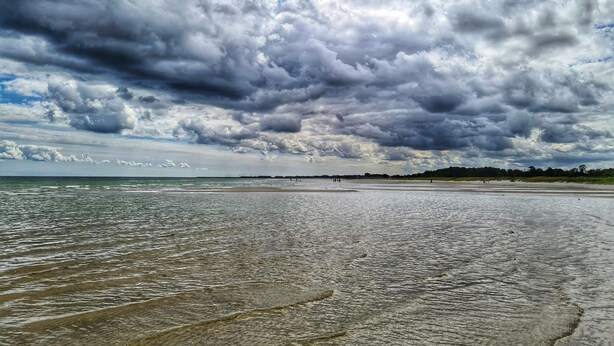 A beach with a wide expanse of sand and water, under a cloudy sky. - 4 Star Holiday Home in Hadsund (Hadsund)