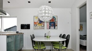 A modern kitchen with a white dining table, green chairs, and a unique white chandelier. - 4 Star Holiday Home in Hadsund (Hadsund)