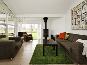 A modern living room with a fireplace, sofas, and a large window. - 4 Star Holiday Home in Hadsund (Hadsund)