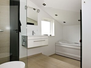 A modern bathroom with a glass shower enclosure, a white vanity with a mirror, a window, and a standalone bathtub. - 4 Star Holiday Home in Hadsund (Hadsund)