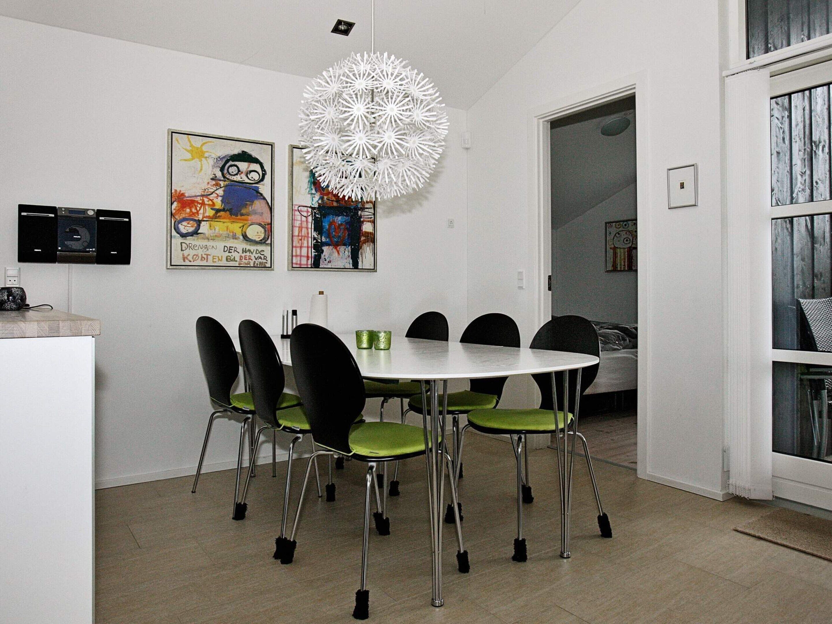 A dining area with a round table, six chairs, and a unique white chandelier.