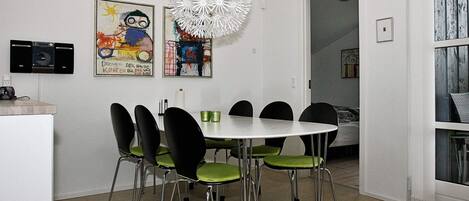 A dining area with a round table, six chairs, and a unique white chandelier.