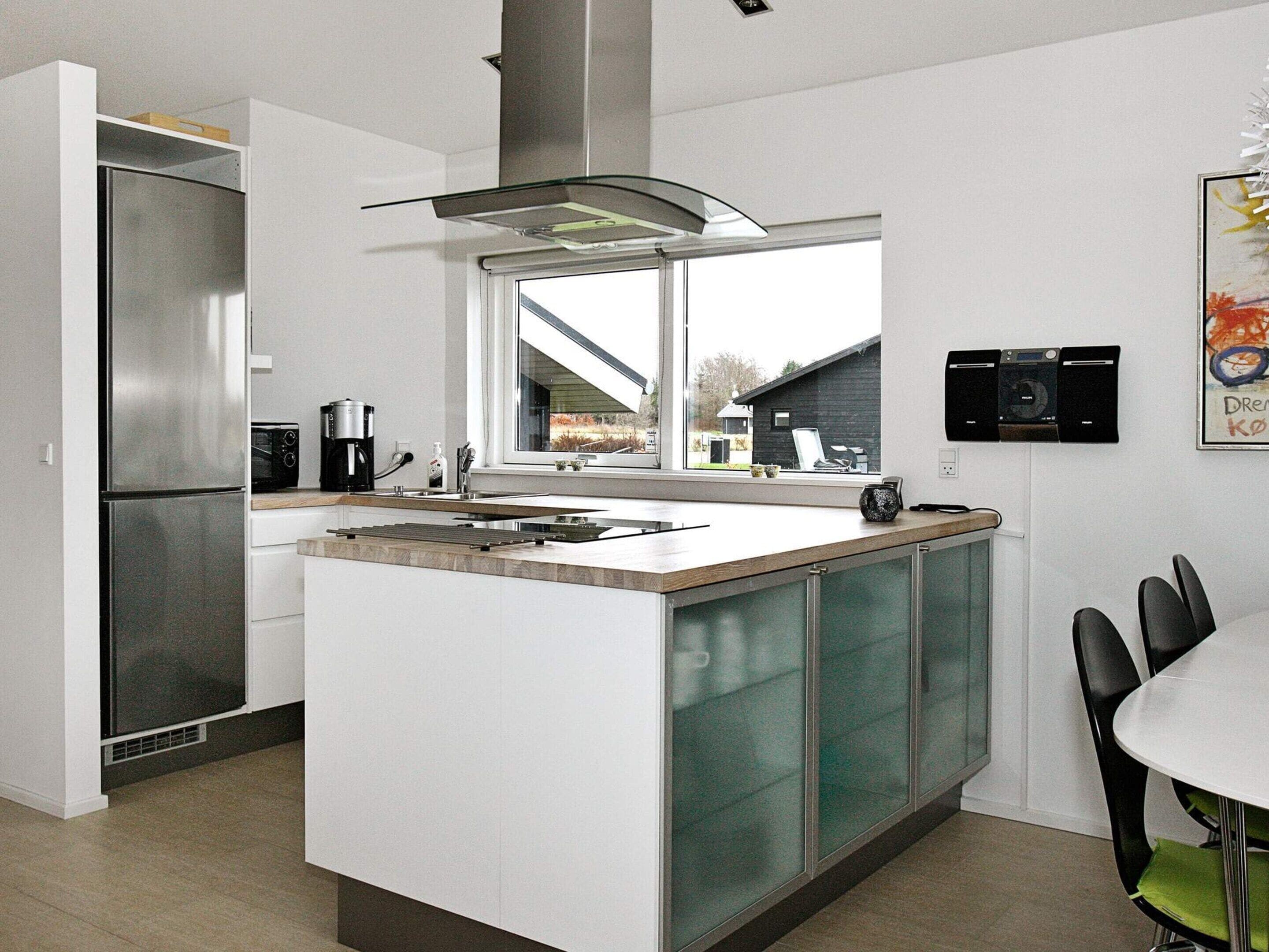 Una cocina moderna con una isla central, electrodomésticos de acero inoxidable y vistas al exterior.
