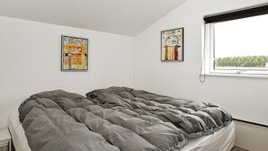 A bedroom with a bed, two wall-mounted artworks, a window with a view, and a small bedside table. - 4 Star Holiday Home in Hadsund (Hadsund)