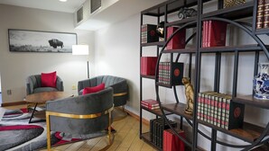 A modern living room with two grey armchairs, a coffee table, a bookshelf with books and decorative items, and a framed picture on the wall. - Pet-Friendly Tulsa-Area Stay with Free Breakfast & Parking (Broken Arrow)