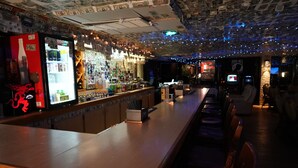 A bar area with a refrigerator stocked with beverages, a bar counter with a cash register, and a seating area with chairs. - Pet-Friendly Tulsa-Area Stay with Free Breakfast & Parking (Broken Arrow)