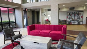 A lobby with a red sofa, grey chairs, a wooden coffee table, and a decorative wall unit. - Pet-Friendly Tulsa-Area Stay with Free Breakfast & Parking (Broken Arrow)