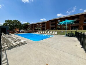 A swimming pool with lounge chairs, a picnic table, and a wooden building with balconies. - Welcome to Royale Relaxation at Pointe Royale in Branson, Missouri! (Branson)