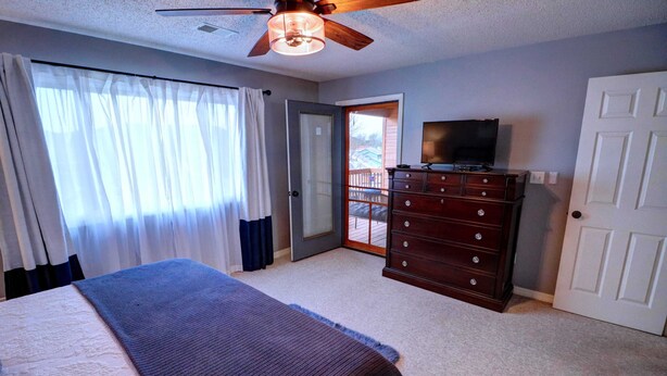 A bedroom with a bed, a dresser, a television, and a door leading to a balcony. - Welcome to Royale Relaxation at Pointe Royale in Branson, Missouri! (Branson)