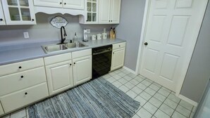 A kitchen with white cabinets, a dishwasher, a sink, and a door. - Welcome to Royale Relaxation at Pointe Royale in Branson, Missouri! (Branson)