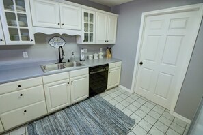 A kitchen with white cabinets, a dishwasher, a sink, and a door. - Welcome to Royale Relaxation at Pointe Royale in Branson, Missouri! (Branson)