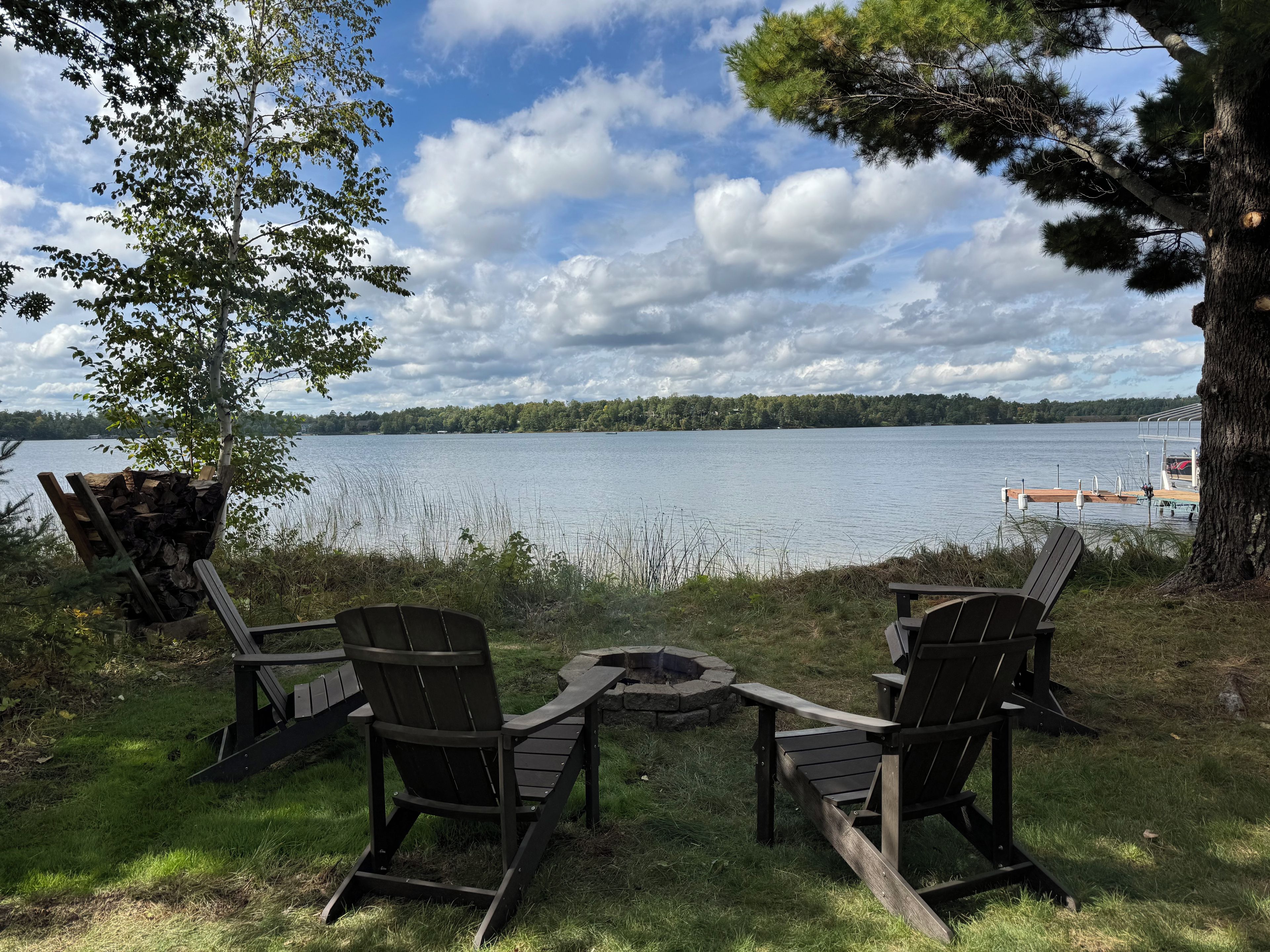 Un'area relax sul lago con sedie Adirondack e un braciere.
