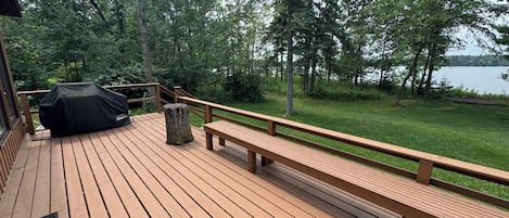 Una terraza de madera con un banco y una parrilla.