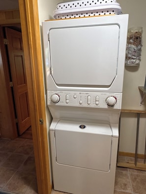 A stacked washer and dryer unit with control knobs and buttons.