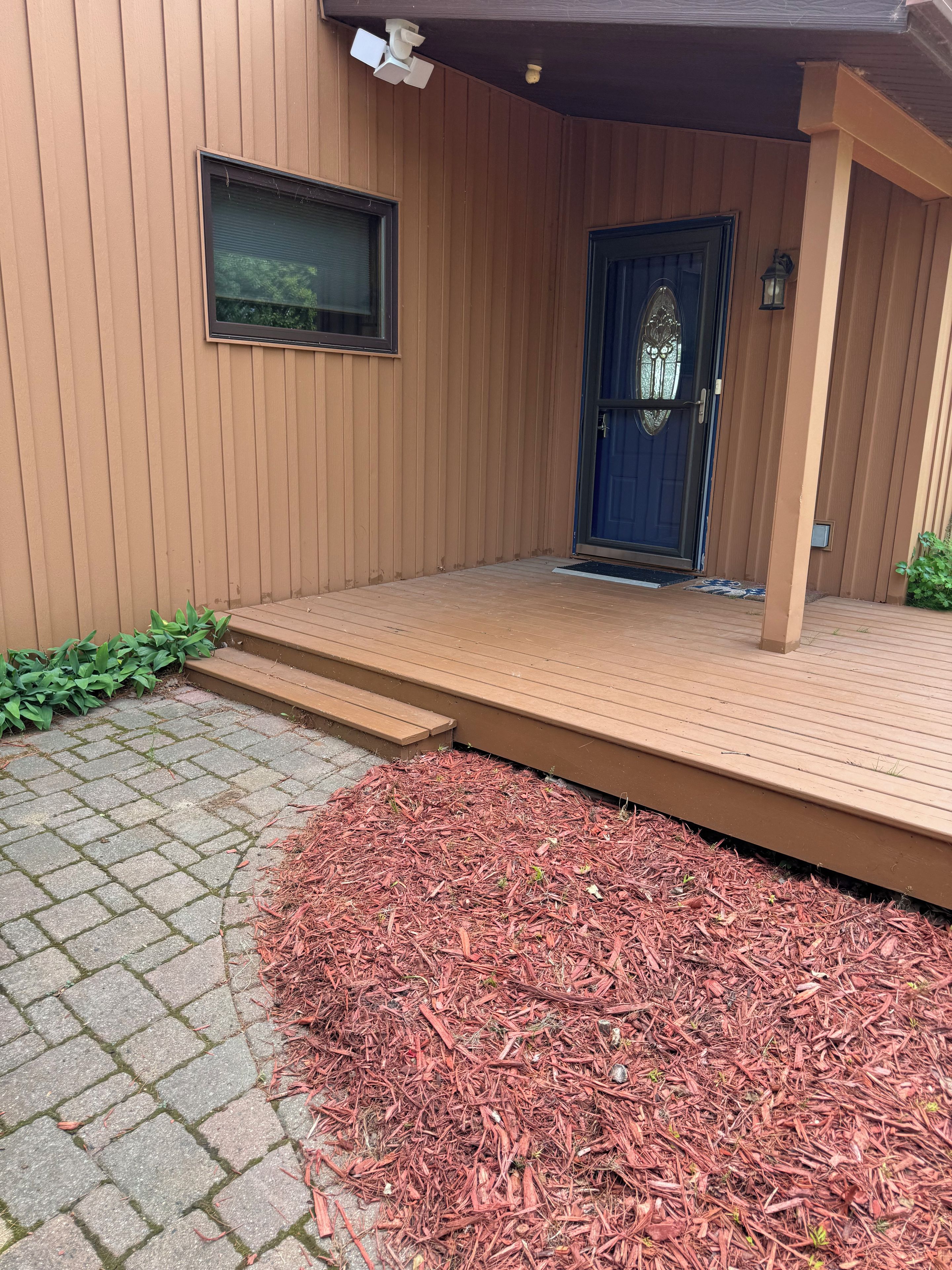 A wooden exterior with a front door, a small window, and a wooden deck leading to the entrance.