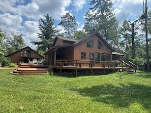 A wooden cabin with a deck and a smaller attached structure.