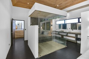 Ein modernes Badezimmer mit einer gläsernen Duschkabine, einem großen Spiegel und minimalistischem Design.
